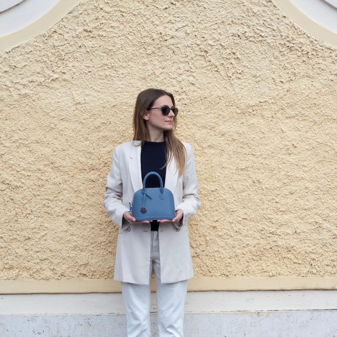 Italian leather mini hand bag with strap, Sofia 20 in fairy color, worn by a model.